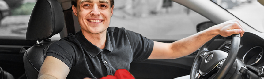 Worker Smiling in Car With Meal Delivery Bags